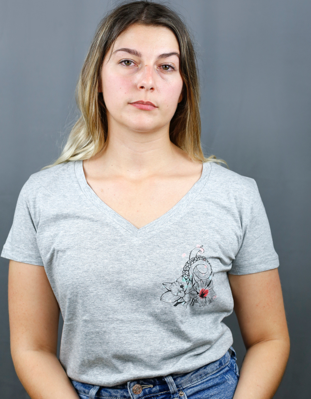 Femme avec T-Shirt gris à col V et visuel noir, vert et rouge de la marque Terribles Nantais