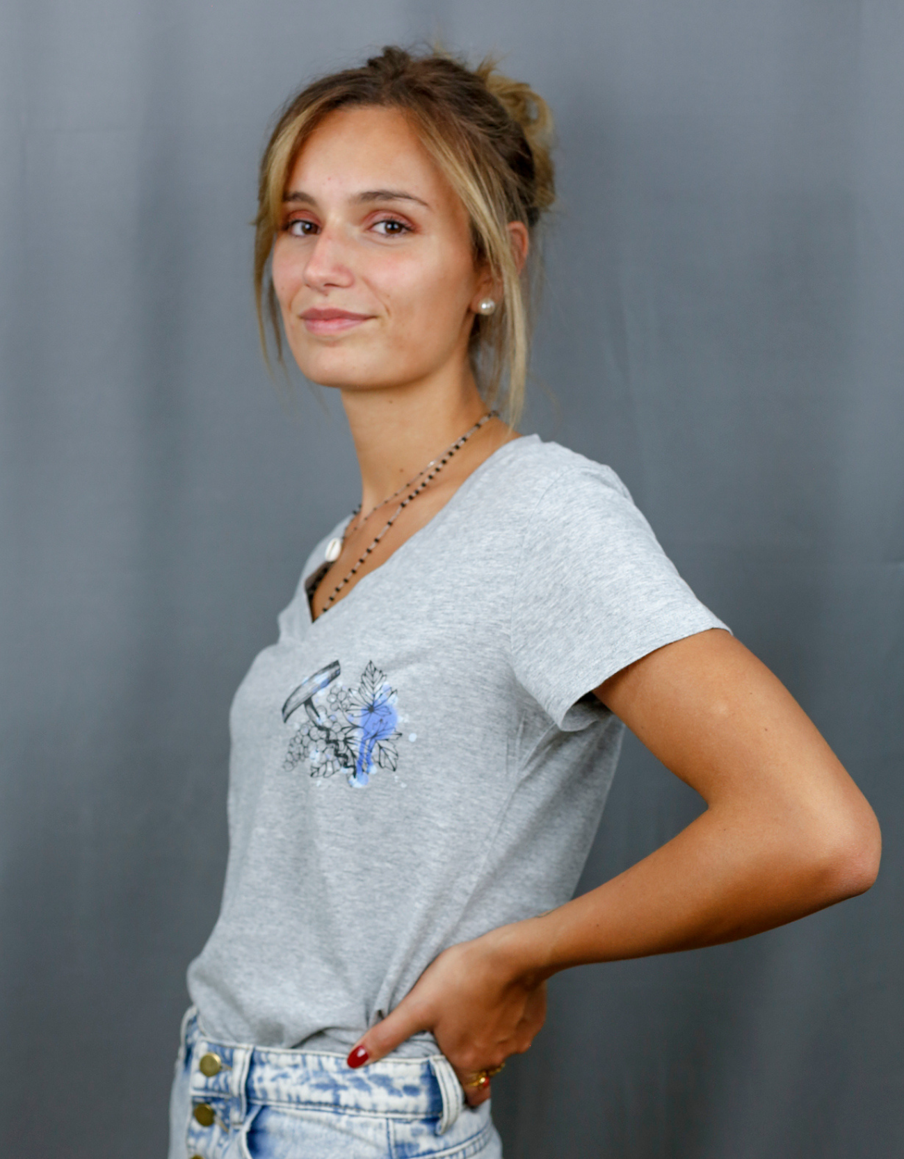 Femme avec T-Shirt gris à col V et visuel noir, bleu et bleu clair de la marque Terribles Nantais