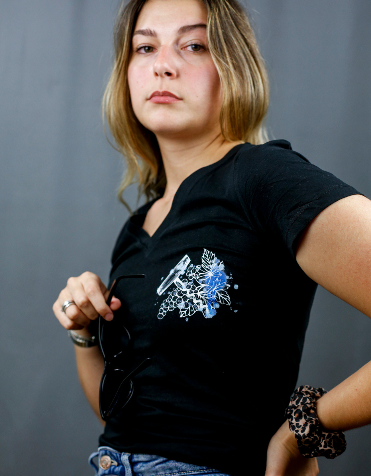 Femme avec T-Shirt noir à col V et visuel blanc, bleu et bleu clair de la marque Terribles Nantais