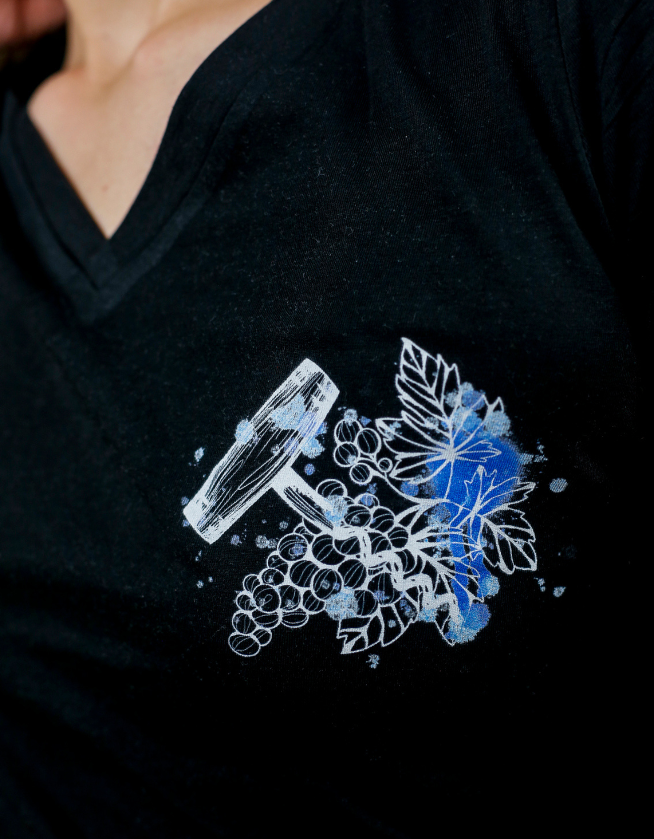 Femme avec T-Shirt noir à col V et visuel blanc, bleu et bleu clair de la marque Terribles Nantais