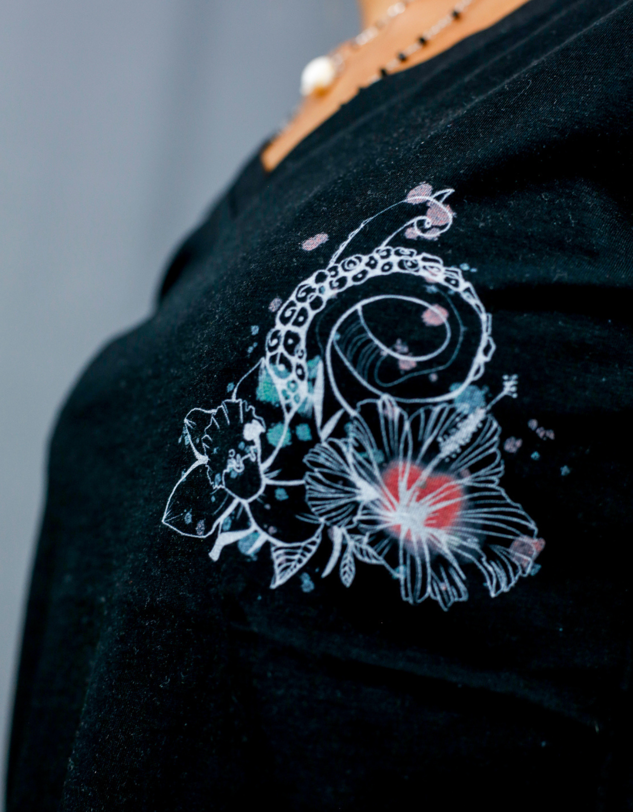 Femme avec T-Shirt noir à col V et visuel blanc, vert et rouge de la marque Terribles Nantais