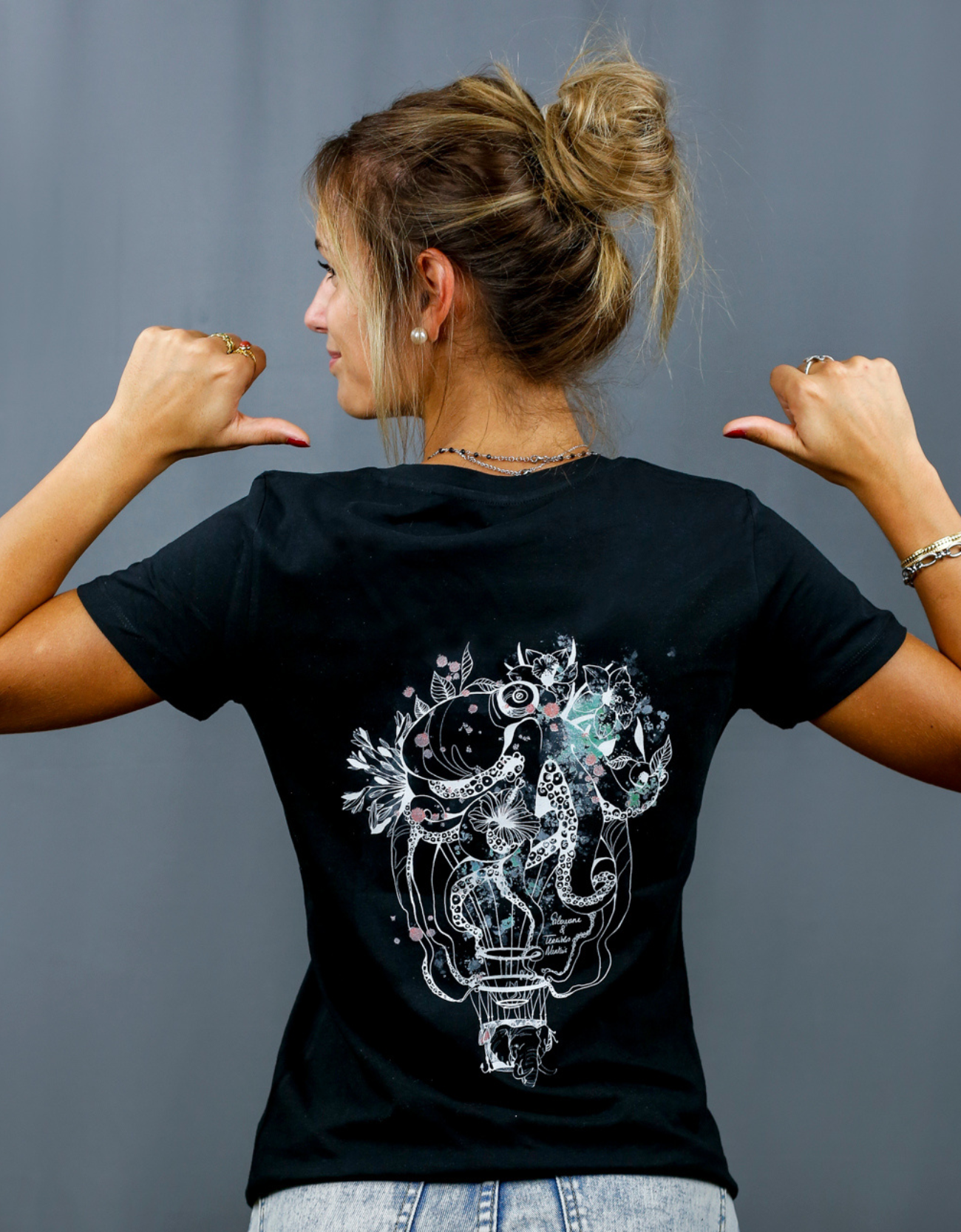 Femme avec T-Shirt noir à col V et visuel blanc, vert et rouge de la marque Terribles Nantais