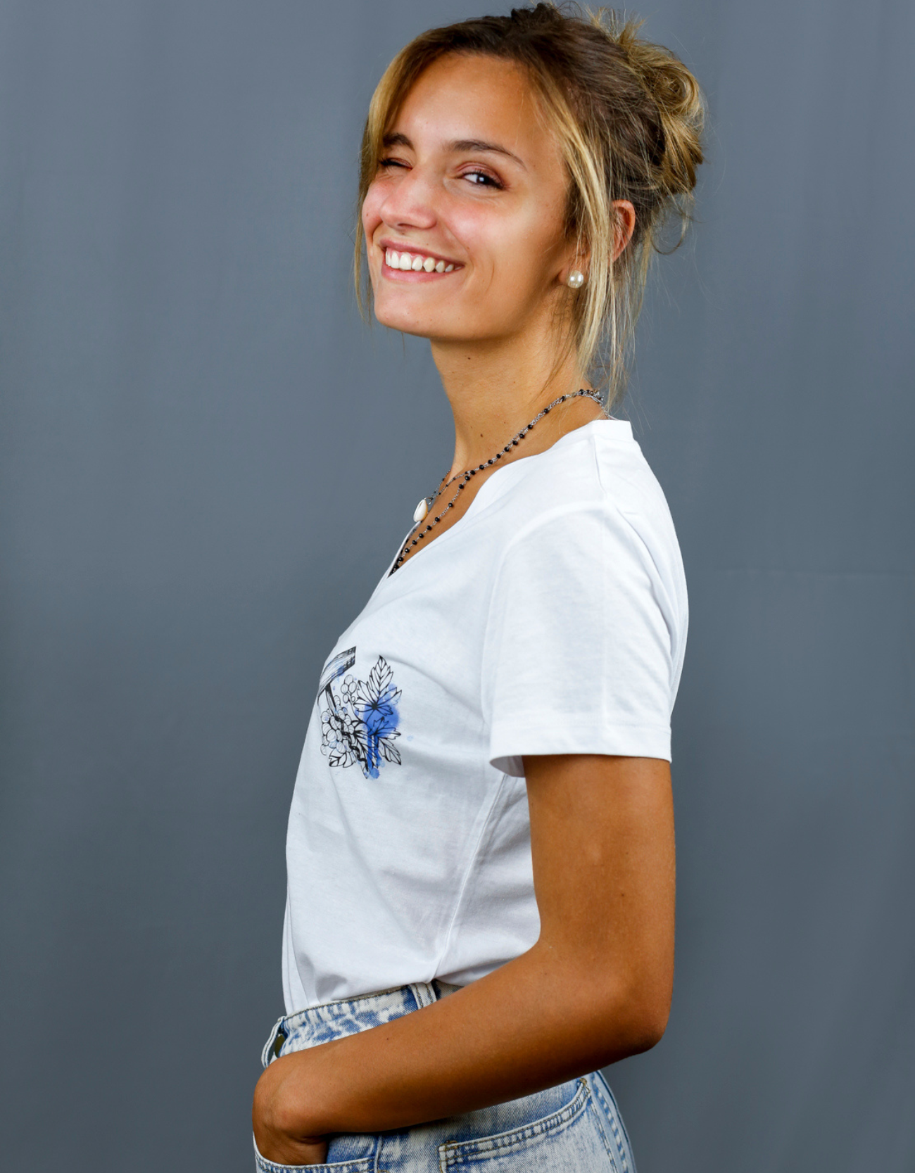 Femme avec T-Shirt blanc à col V et visuel noir, bleu et bleu clair de la marque Terribles Nantais