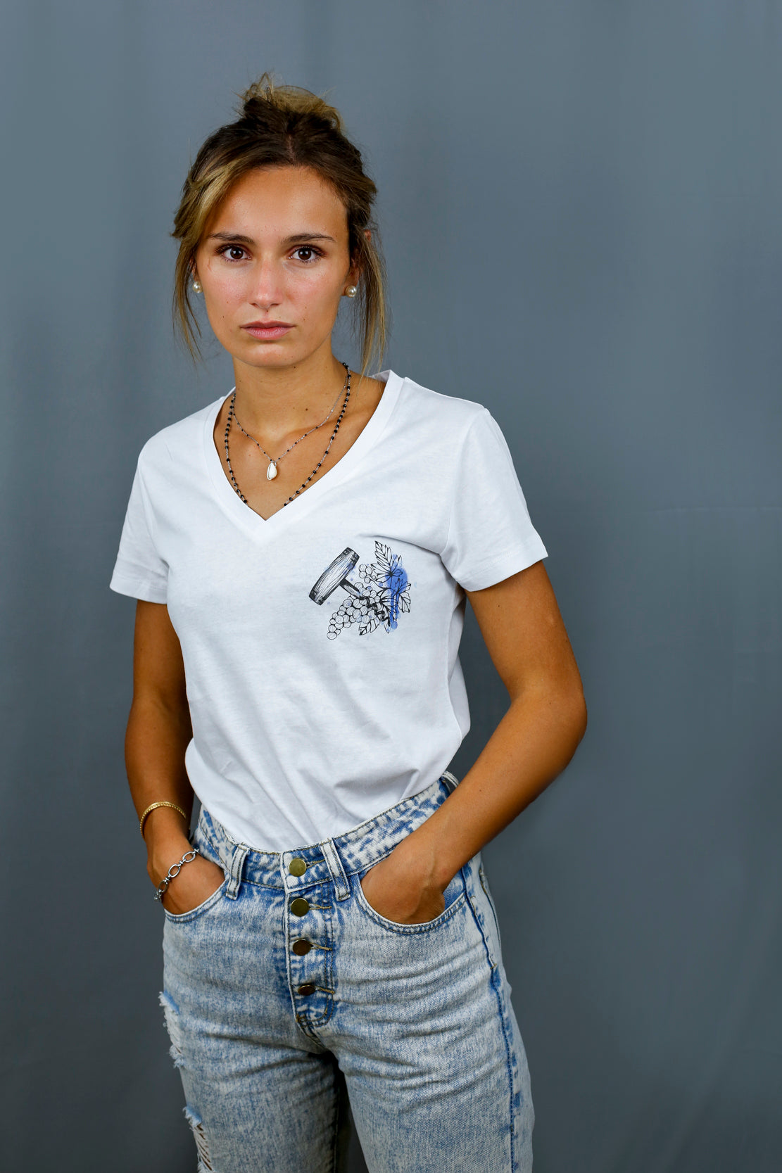 Femme avec T-Shirt blanc à col V et visuel noir, bleu et bleu clair de la marque Terribles Nantais