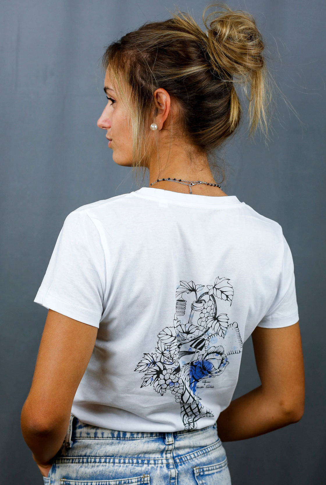 Femme avec T-Shirt blanc à col V et visuel noir, bleu et bleu clair de la marque Terribles Nantais