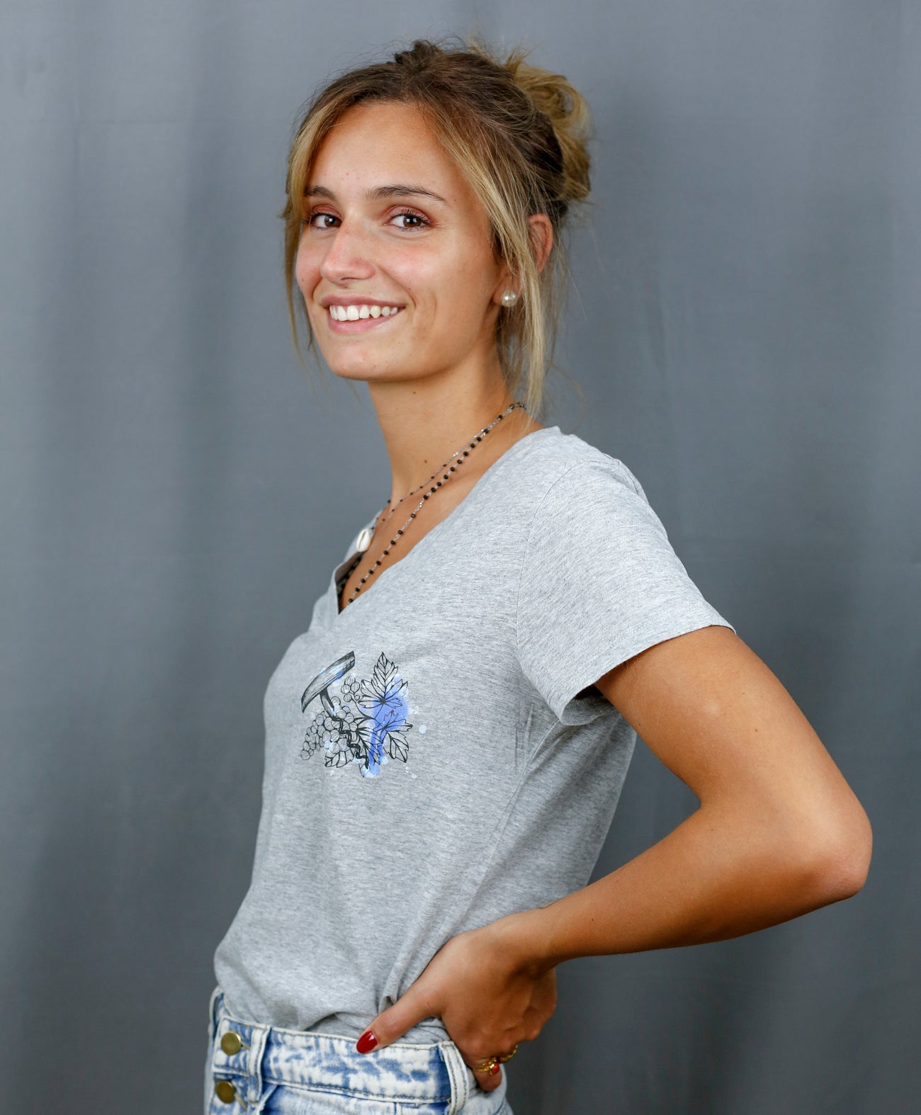 Femme avec T-Shirt gris à col V et visuel noir, bleu et bleu clair de la marque Terribles Nantais