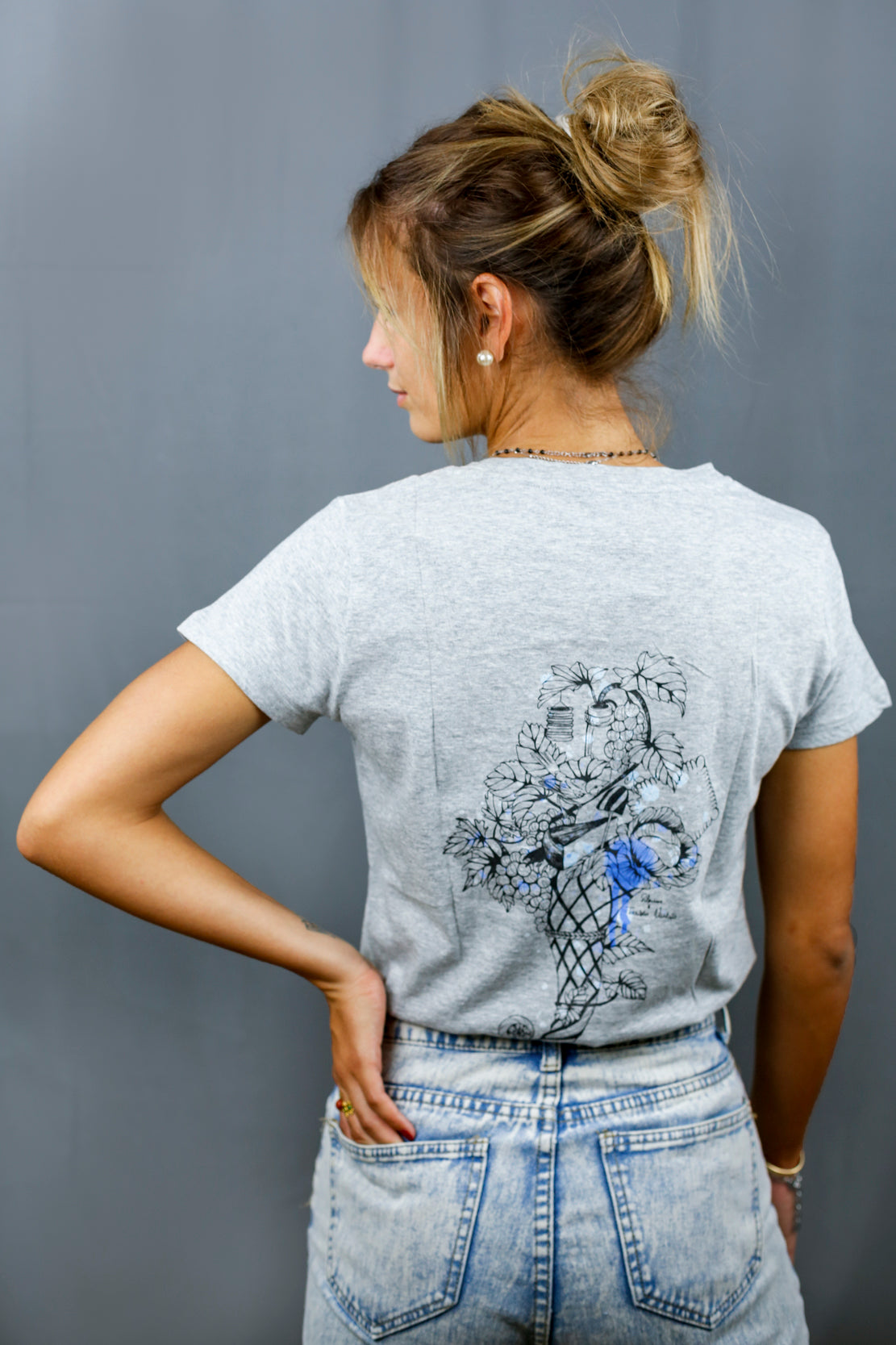 Femme avec T-Shirt gris à col V et visuel noir, bleu et bleu clair de la marque Terribles Nantais