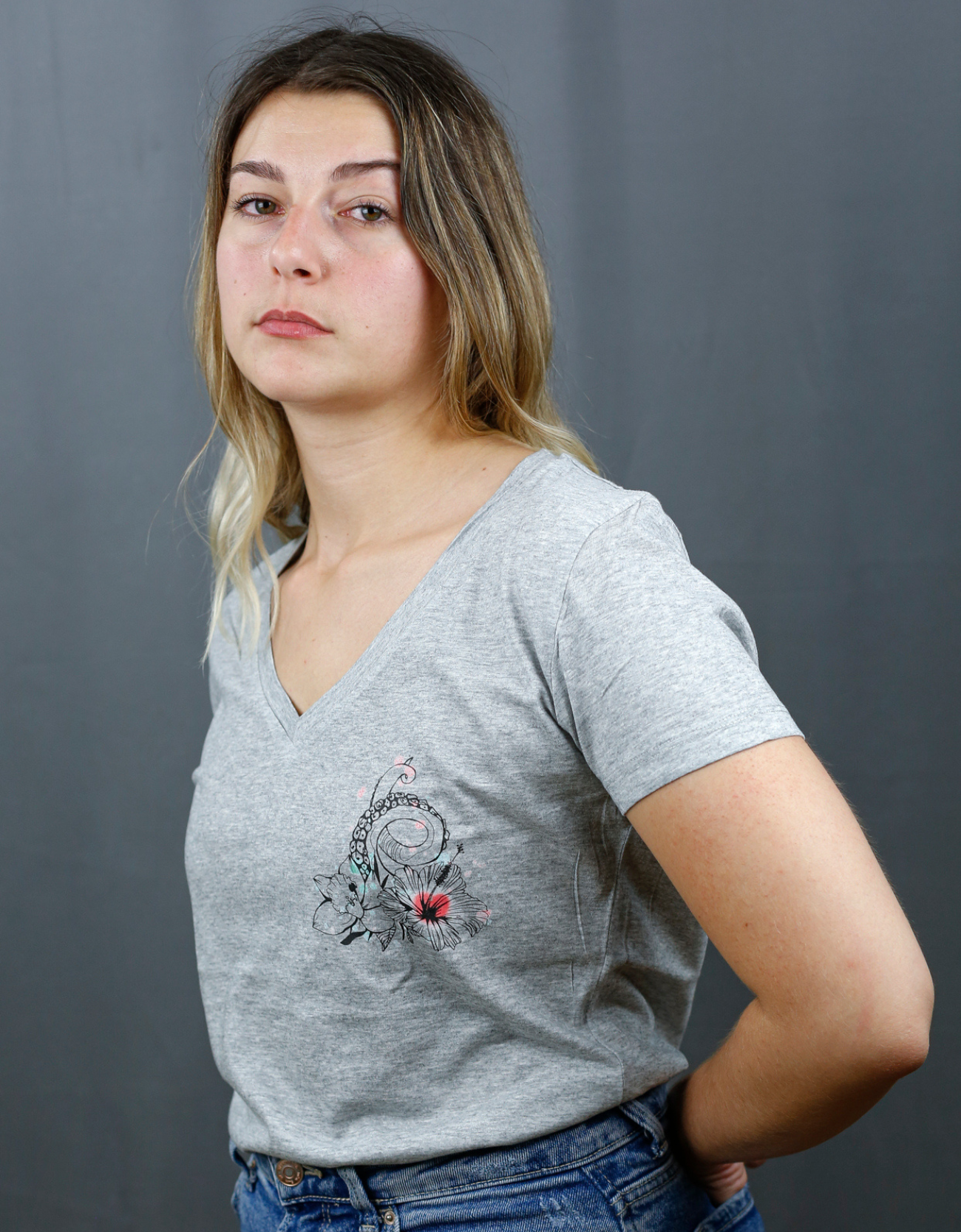 Femme avec T-Shirt gris à col V et visuel noir, vert et rouge de la marque Terribles Nantais