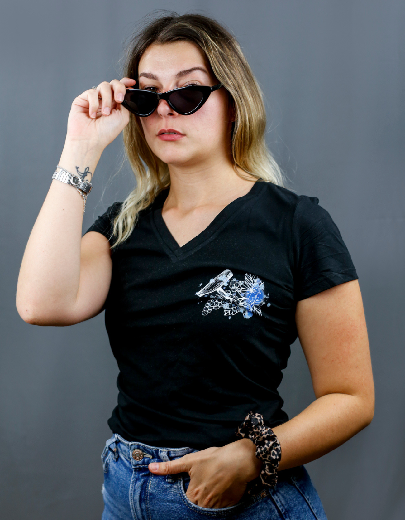 Femme avec T-Shirt noir à col V et visuel blanc, bleu et bleu clair de la marque Terribles Nantais