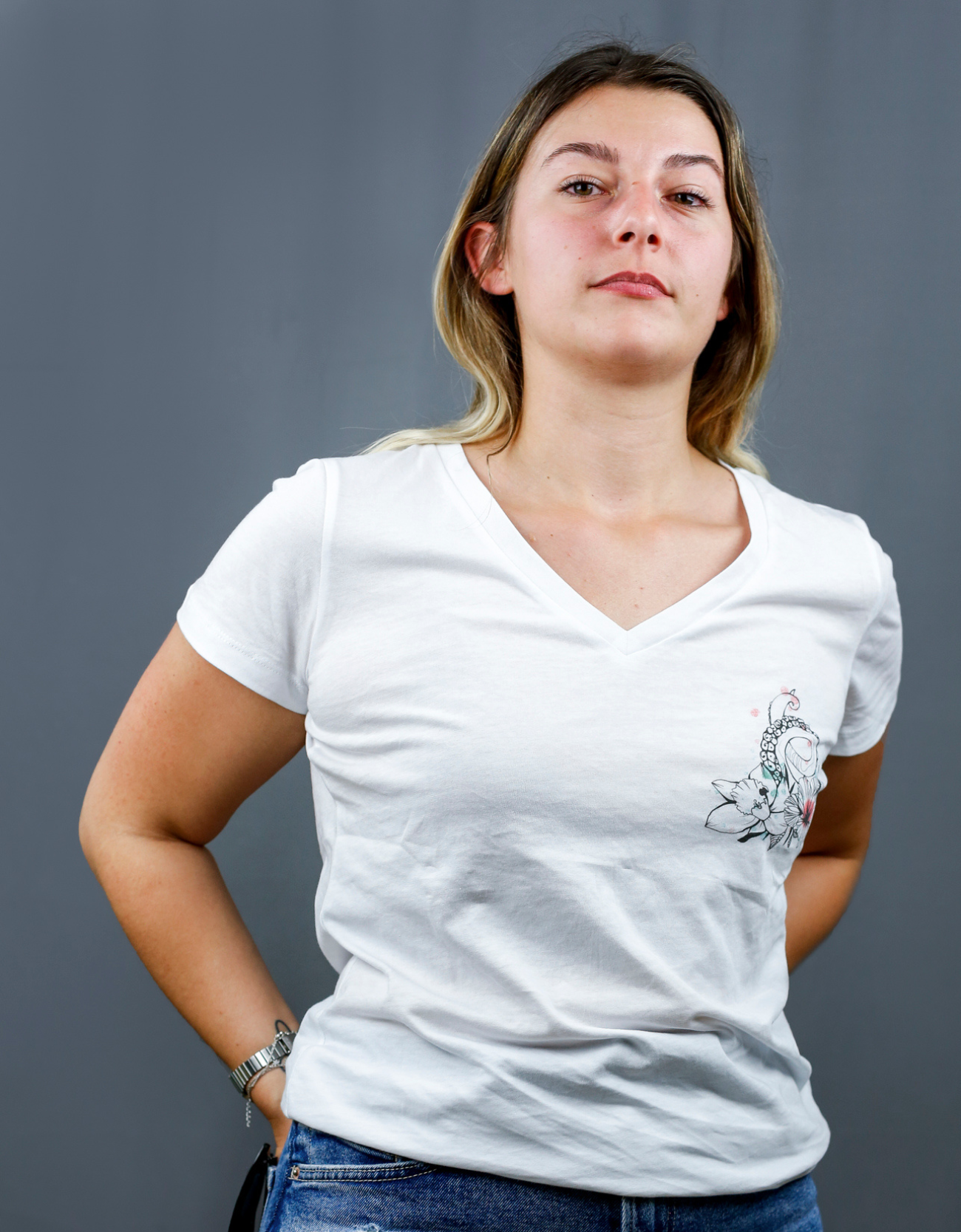 Femme avec T-Shirt blanc à col V et visuel noir, vert et rouge de la marque Terribles Nantais