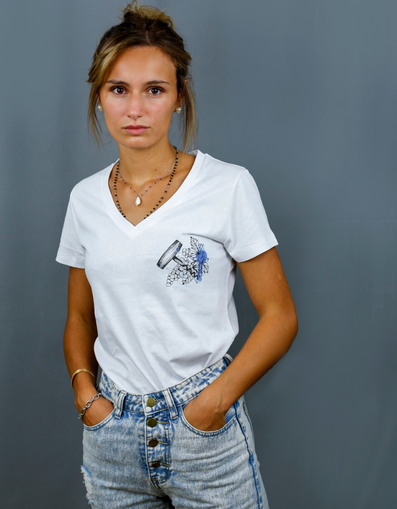 Femme avec T-Shirt blanc à col V et visuel noir, bleu et bleu clair de la marque Terribles Nantais