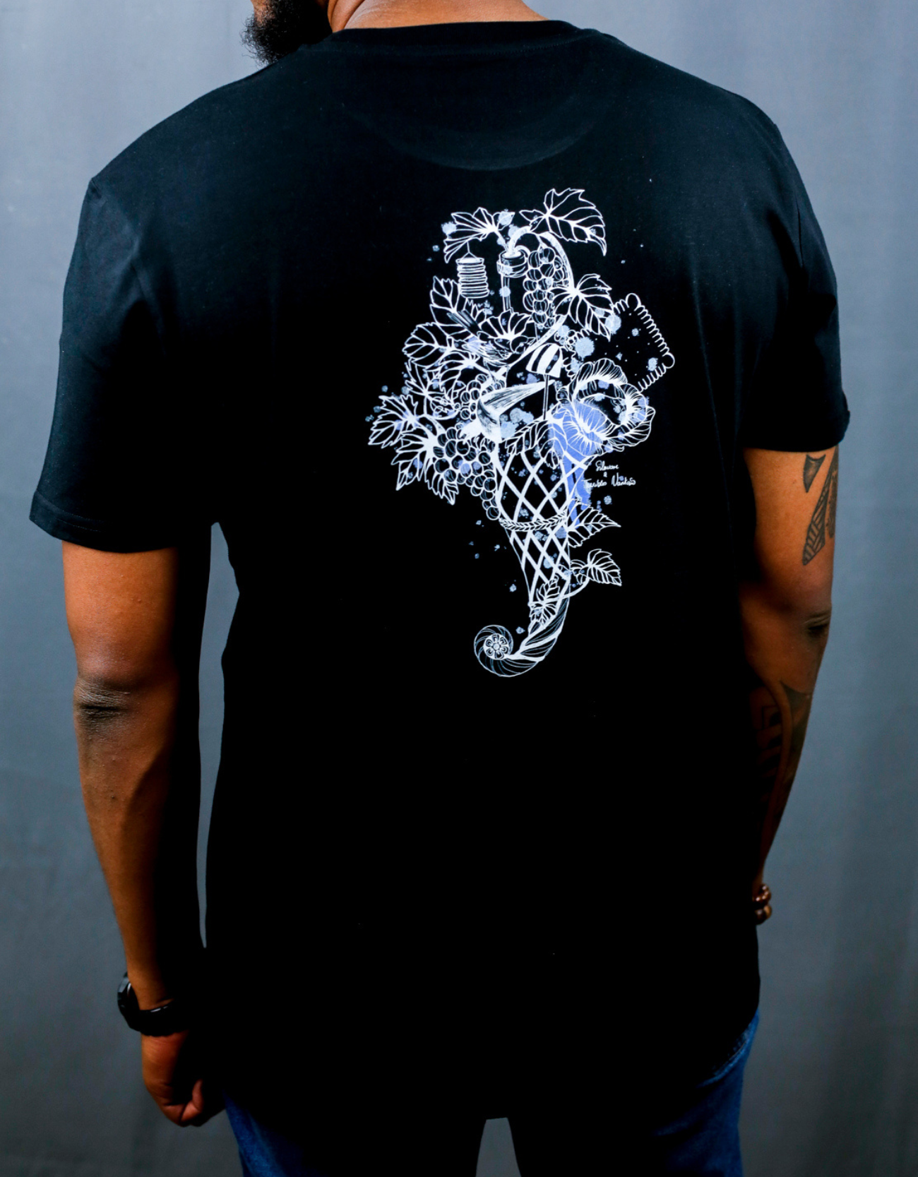 Homme avec T-Shirt noir à col rond et visuel blanc, bleu et bleu clair de la marque Terribles Nantais