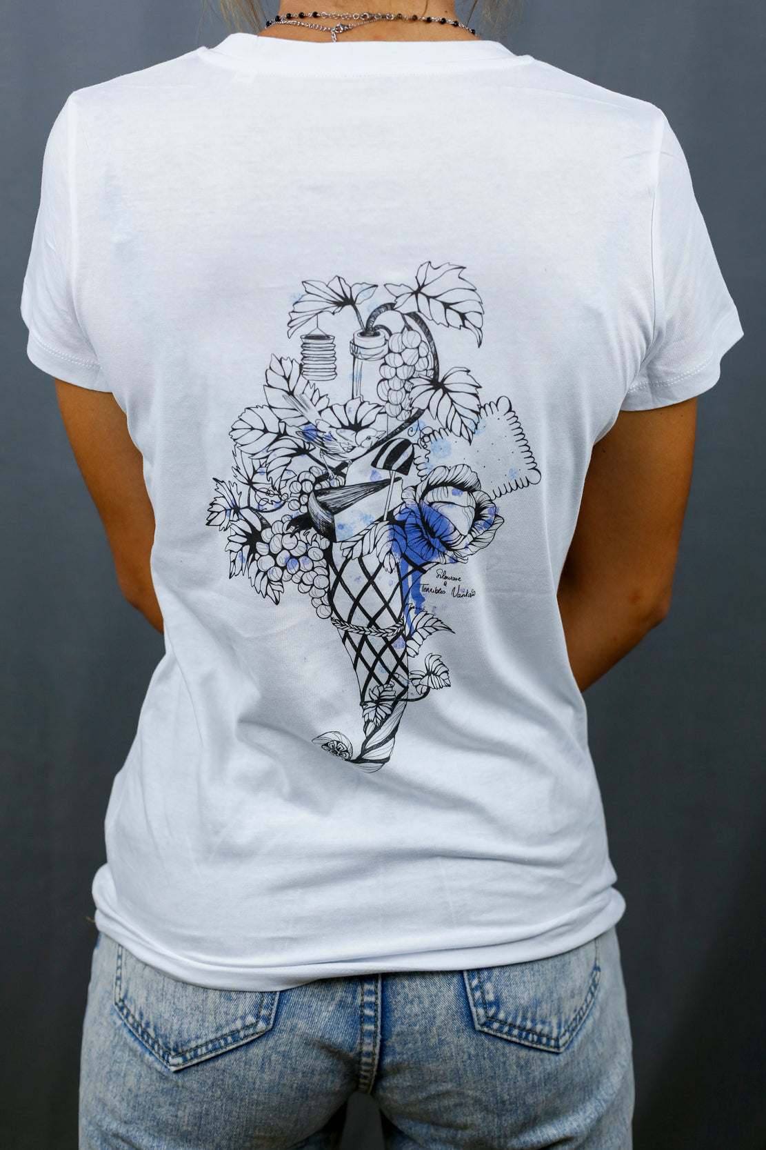 Femme avec T-Shirt blanc à col V et visuel noir, bleu et bleu clair de la marque Terribles Nantais