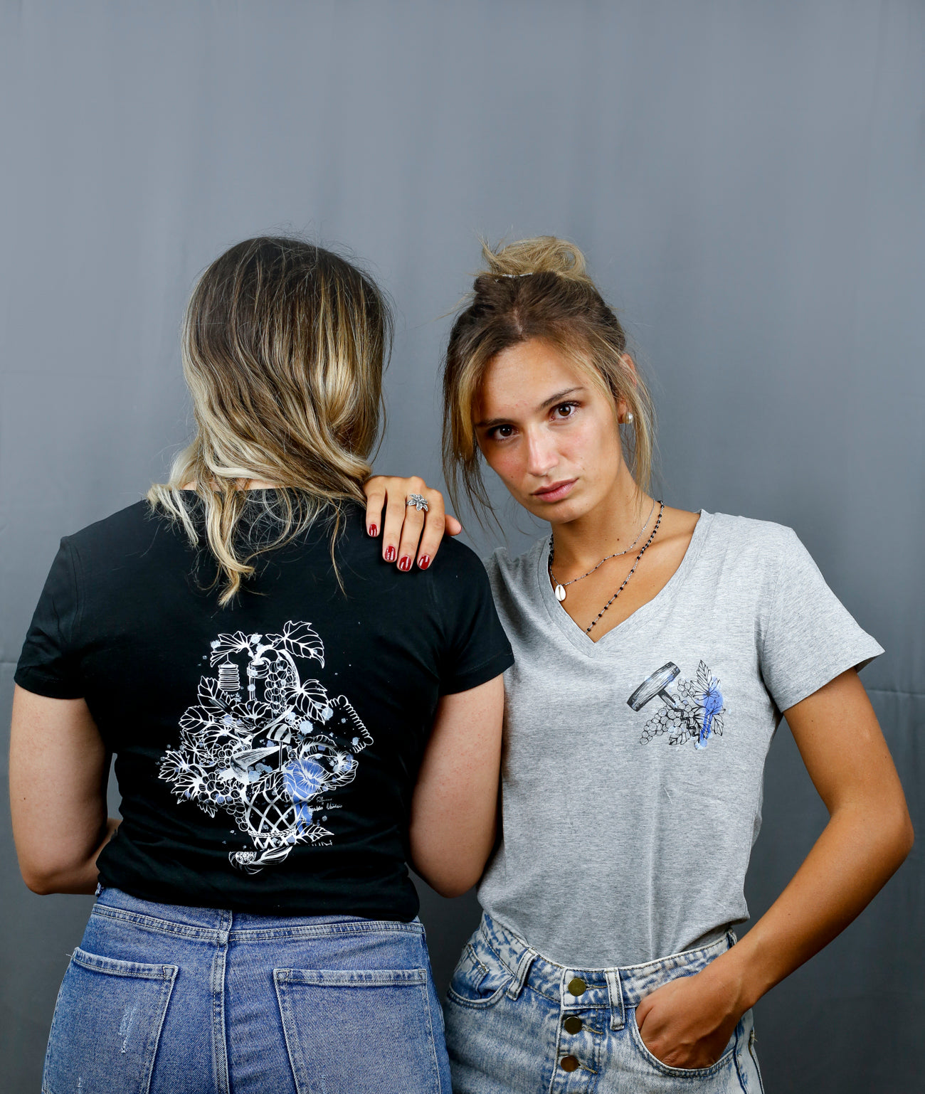 Deux Femmes avec des T-Shirts gris et noirs à col V et visuel noir, bleu et bleu clair de la marque Terribles Nantais