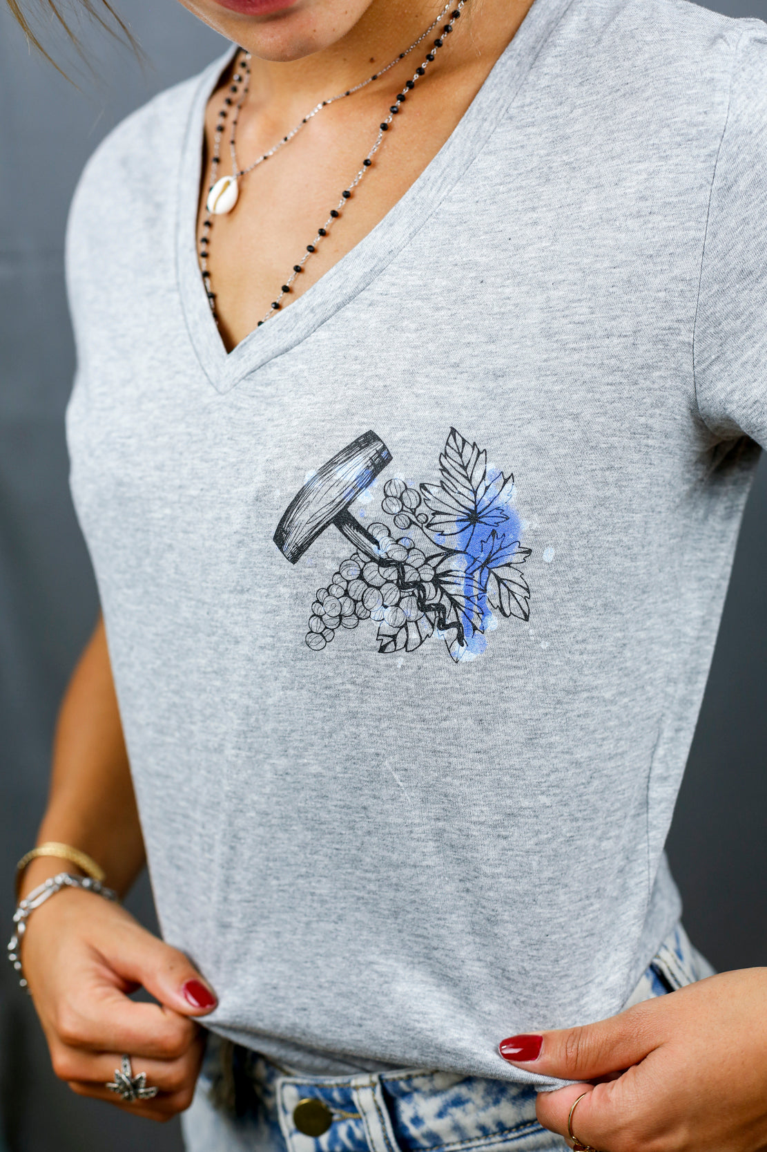 Femme avec T-Shirt gris à col V et visuel noir, bleu et bleu clair de la marque Terribles Nantais